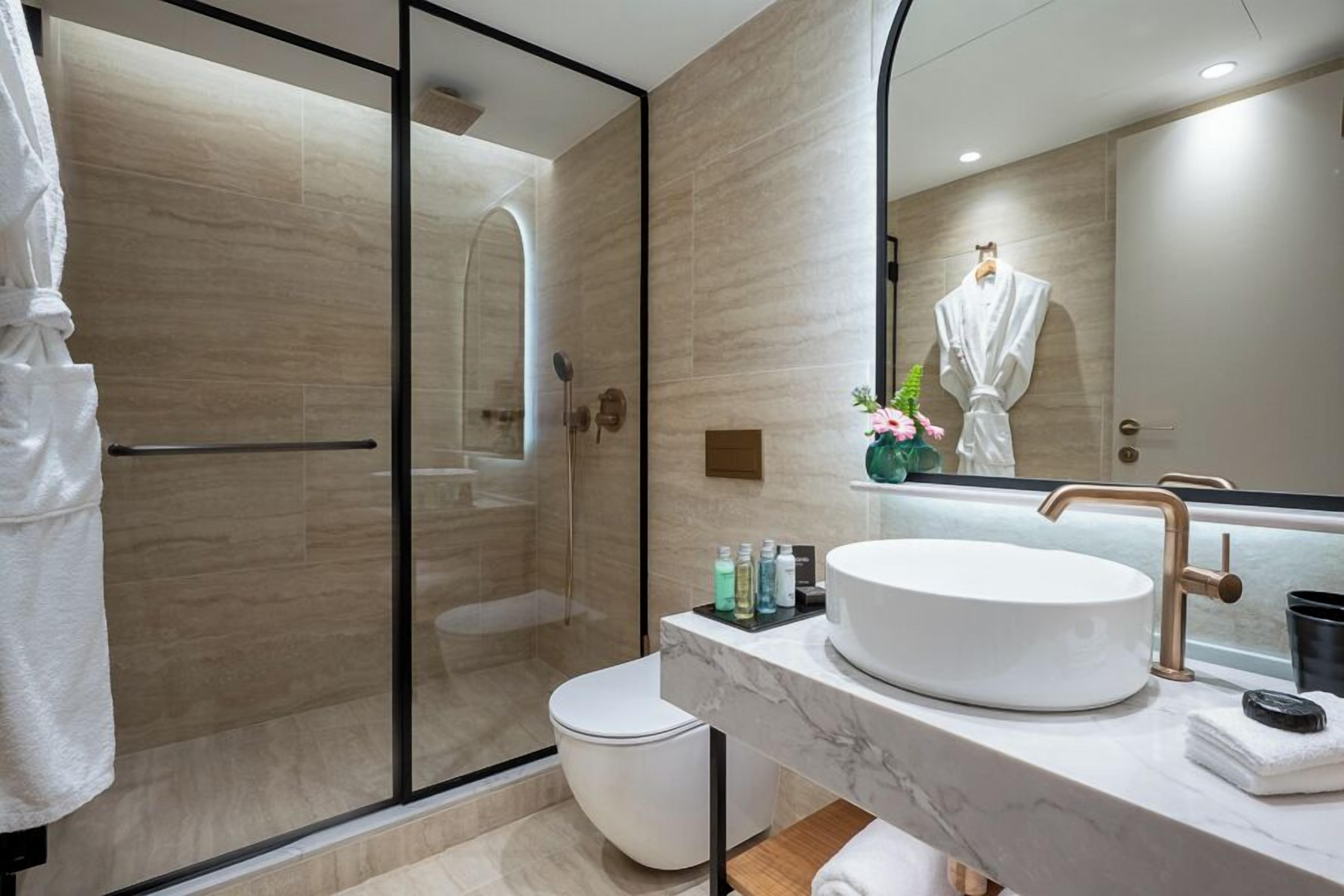 Un baño moderno con cabina de ducha de vidrio, un lavabo blanco y un espejo grande.