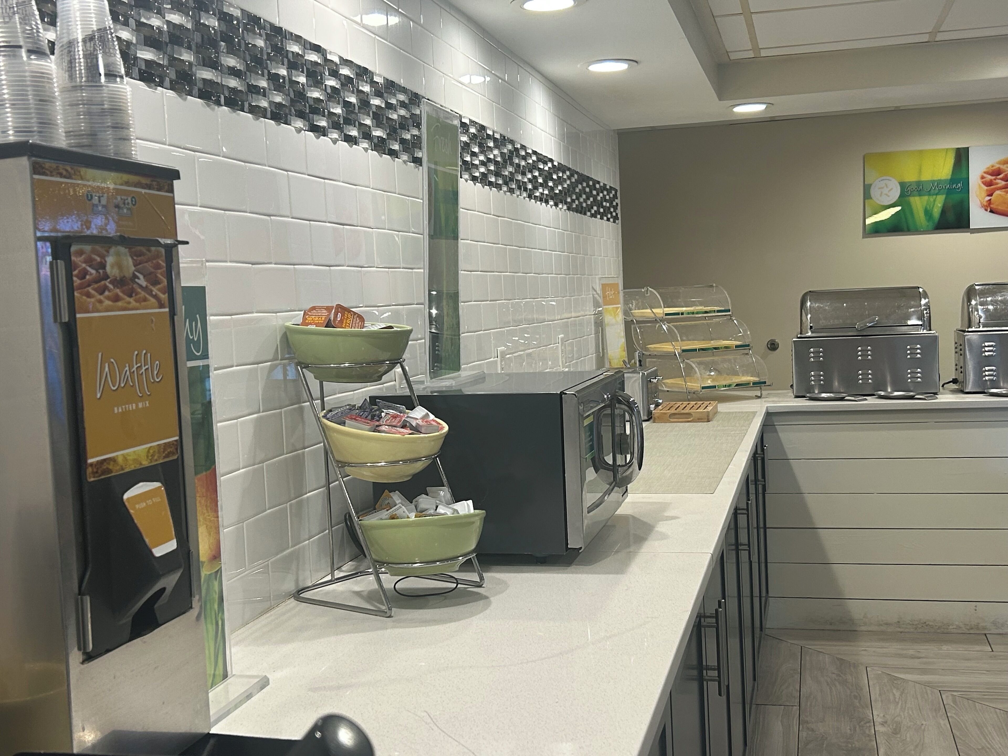 Ein Frühstücksbuffet mit Automaten für Waffeln, einer Kaffeemaschine und einer Auswahl an Waffeln.