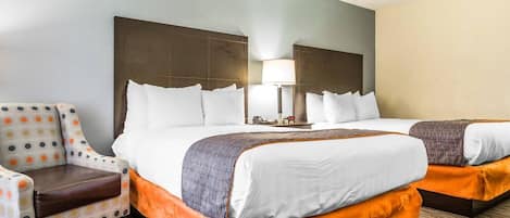 Una habitación de hotel con una cama grande, dos mesitas de noche, una silla y una lámpara.