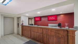 Ein Empfangsbereich mit Holztresen, roter Wand und Schild mit der Angabe kostenloses WLAN in allen Zimmern.
