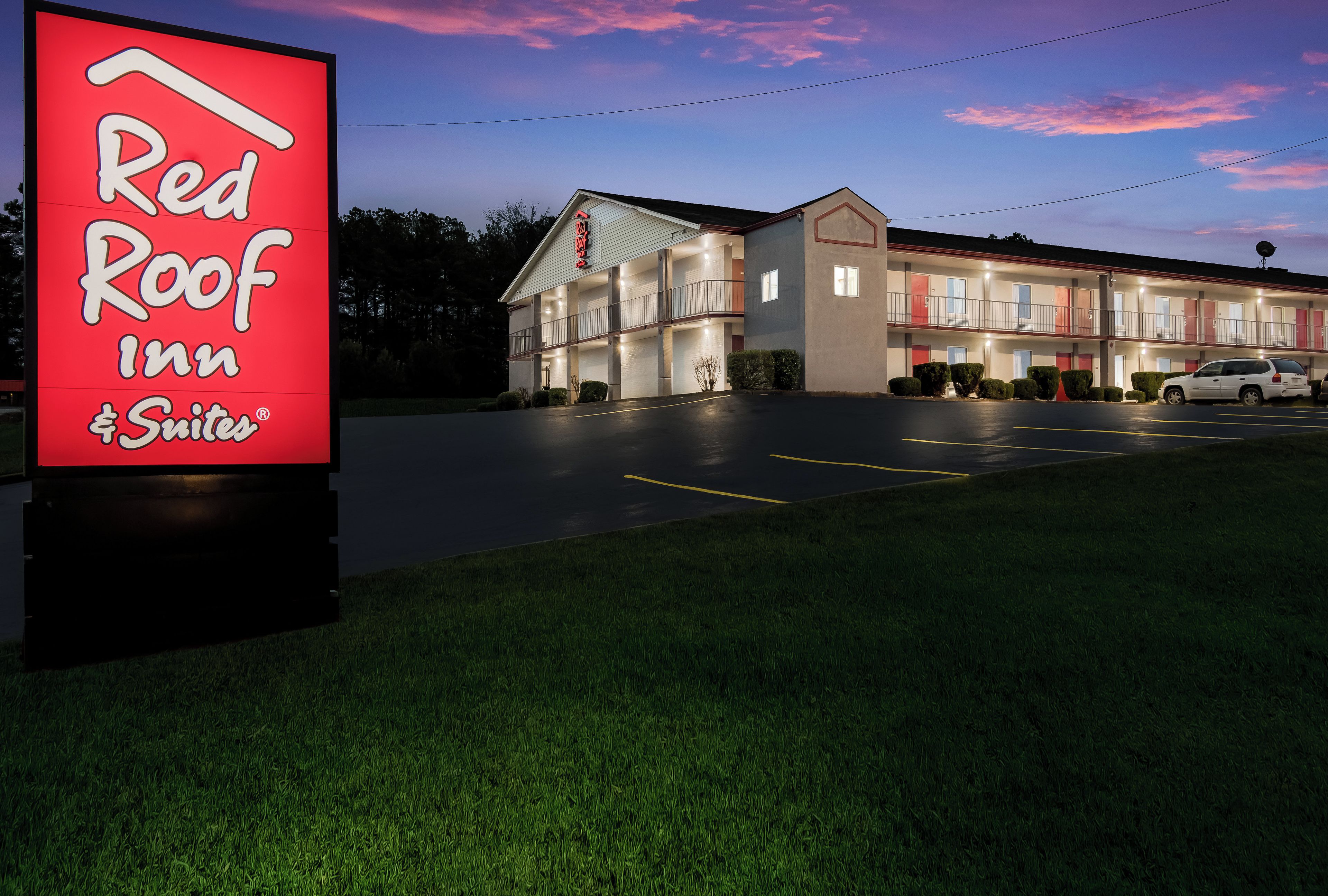 Un hôtel Red Roof Inn & Suites avec un bâtiment à deux étages, un parking et un ciel dégagé.