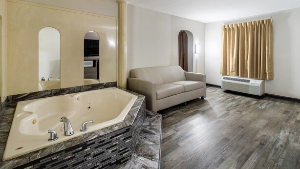 Ein Badezimmer mit einer großen Badewanne, einem beigen Sofa und einer Wand-Klimaanlage.