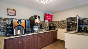 Eine moderne Küche mit einer Kaffeestation, einem Fruchtsaftspender und einem Kühlschrank.