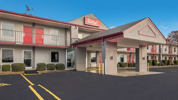 A Red Roof Inn with a two-story building, a covered parking area, and a clear blue sky. - Red Roof Inn & Suites Jackson, TN (Jackson)