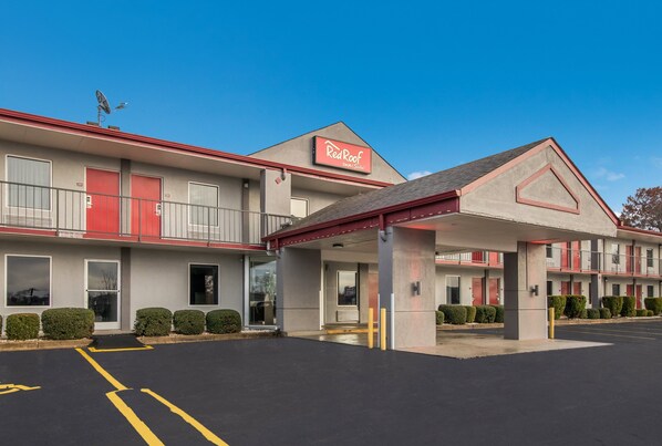 A motel with a red and white facade, multiple balconies, and a parking lot. - Red Roof Inn & Suites Jackson, TN (Jackson)
