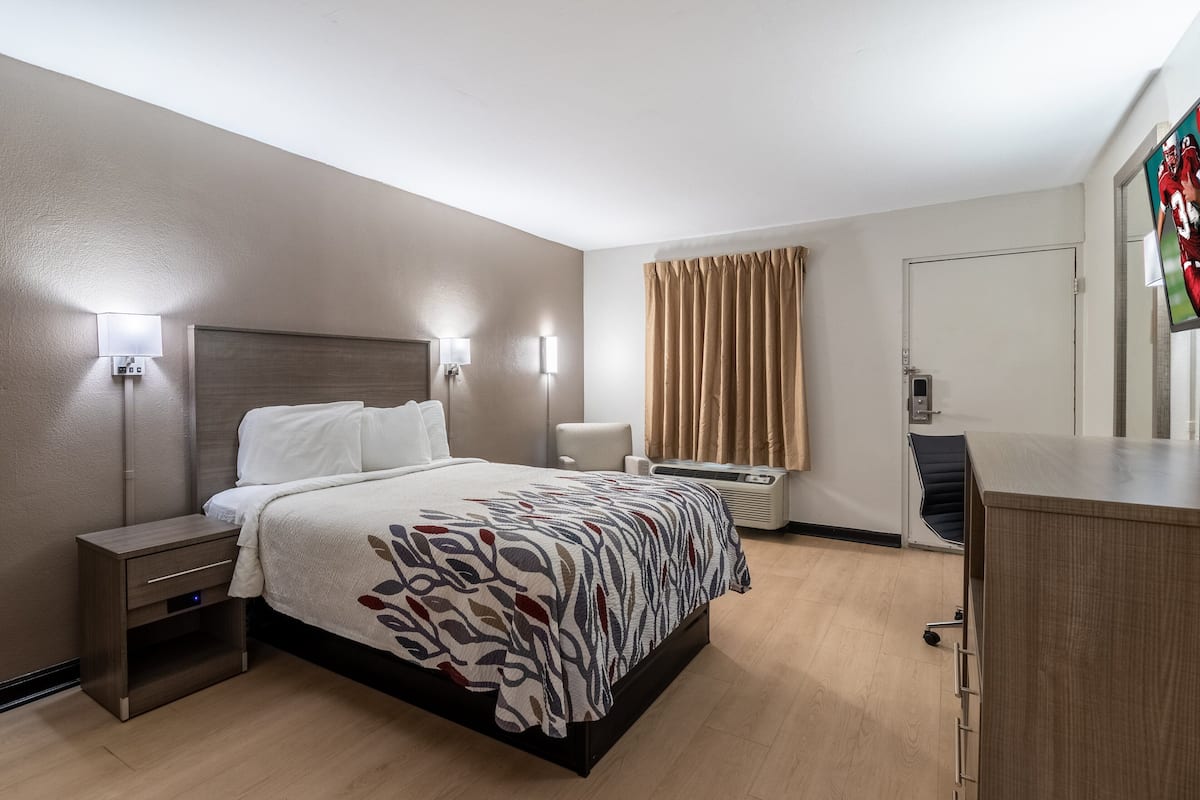 A hotel room with a bed, bedside tables, a desk, and a chair.