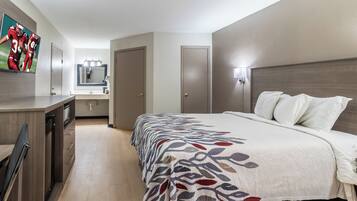 A hotel room with a bed, a desk, a mirror, and a television.