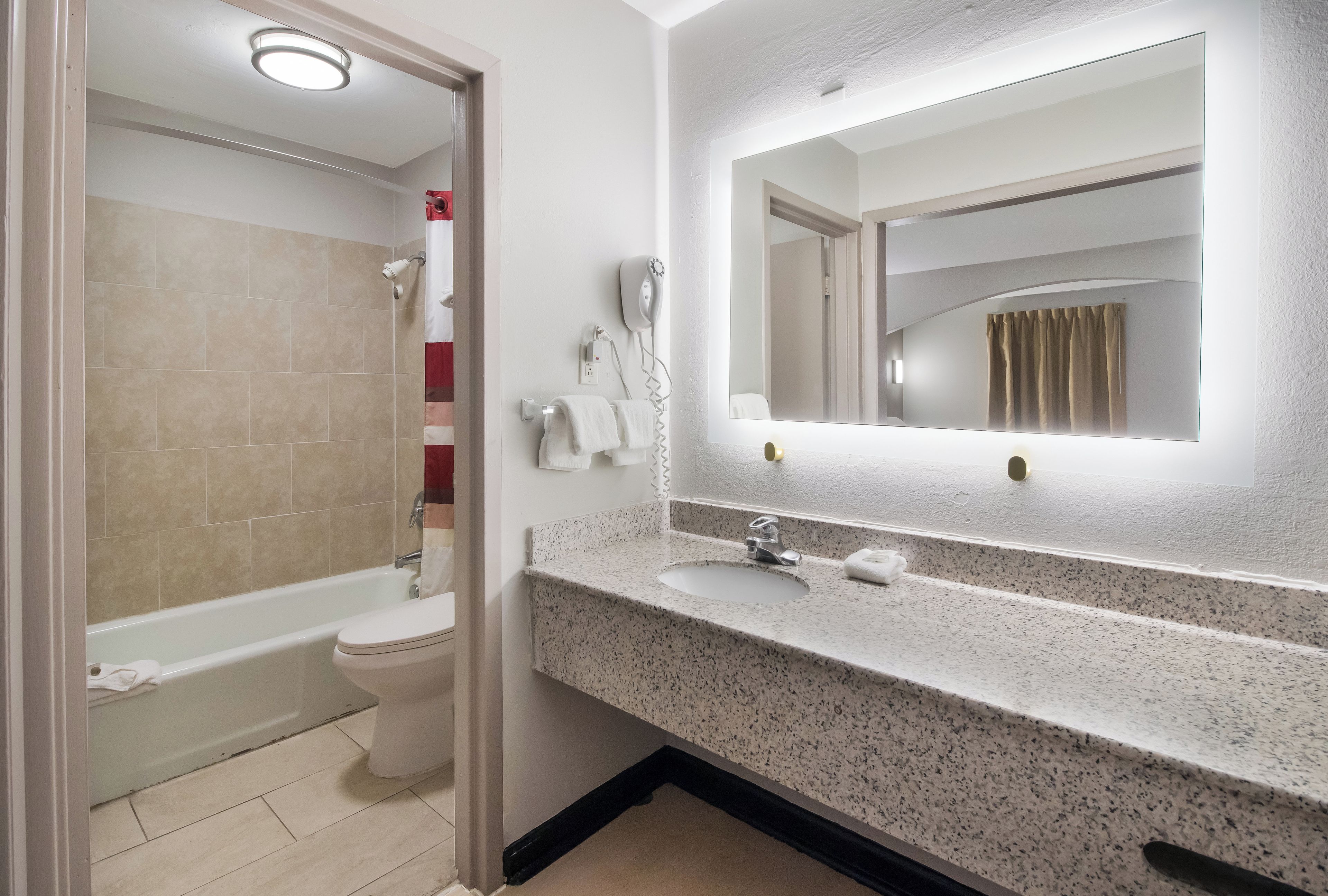 A bathroom with a bathtub, toilet, and a sink with a mirror above it.