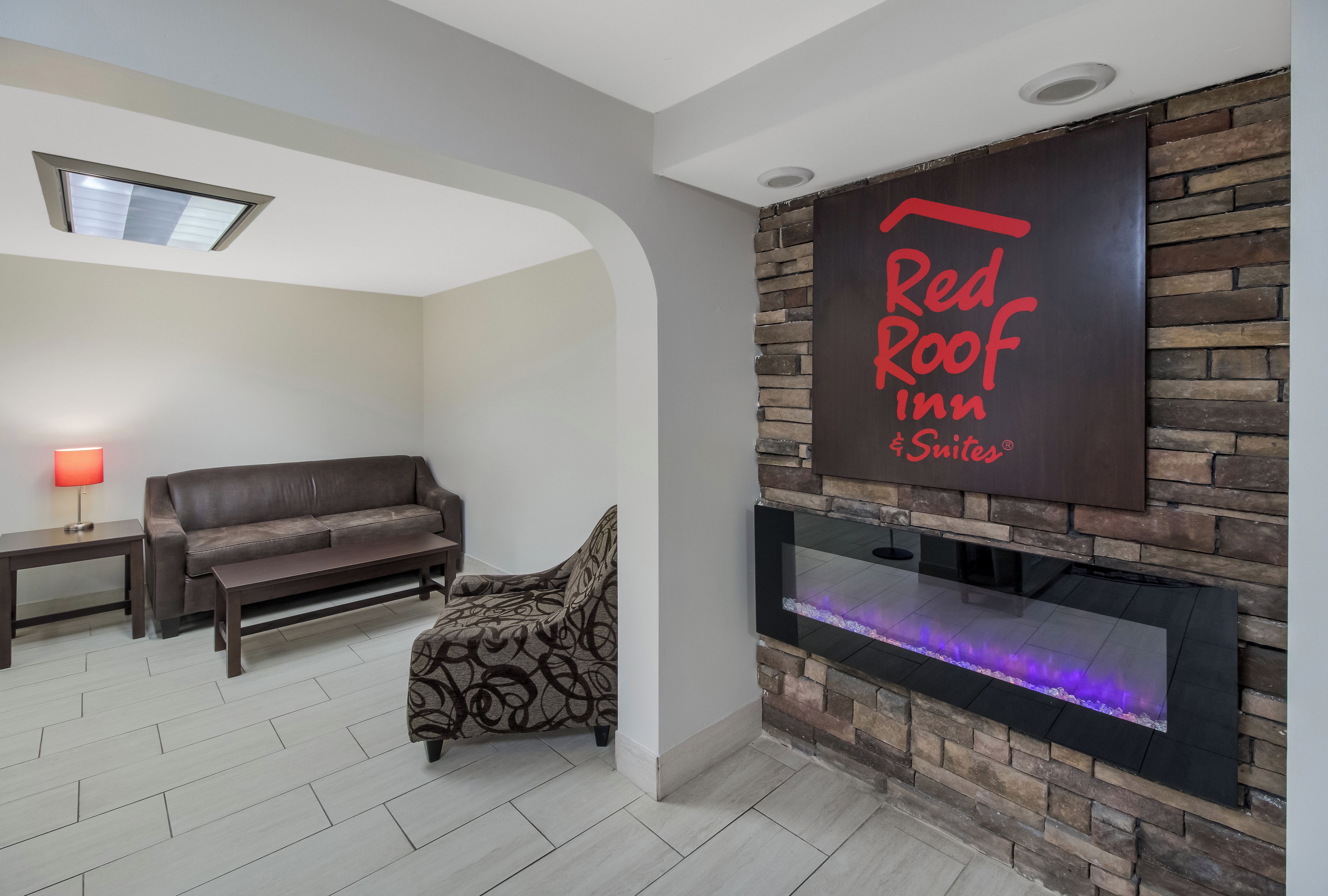 A modern living room with a fireplace, a sofa, a patterned armchair, and a wall-mounted sign.