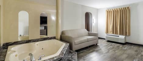 A modern bathroom with a freestanding bathtub, a beige sofa, and a large mirror.