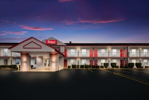 A motel with a red and white facade, multiple balconies, and a parking lot. - Red Roof Inn & Suites Jackson, TN (Jackson)