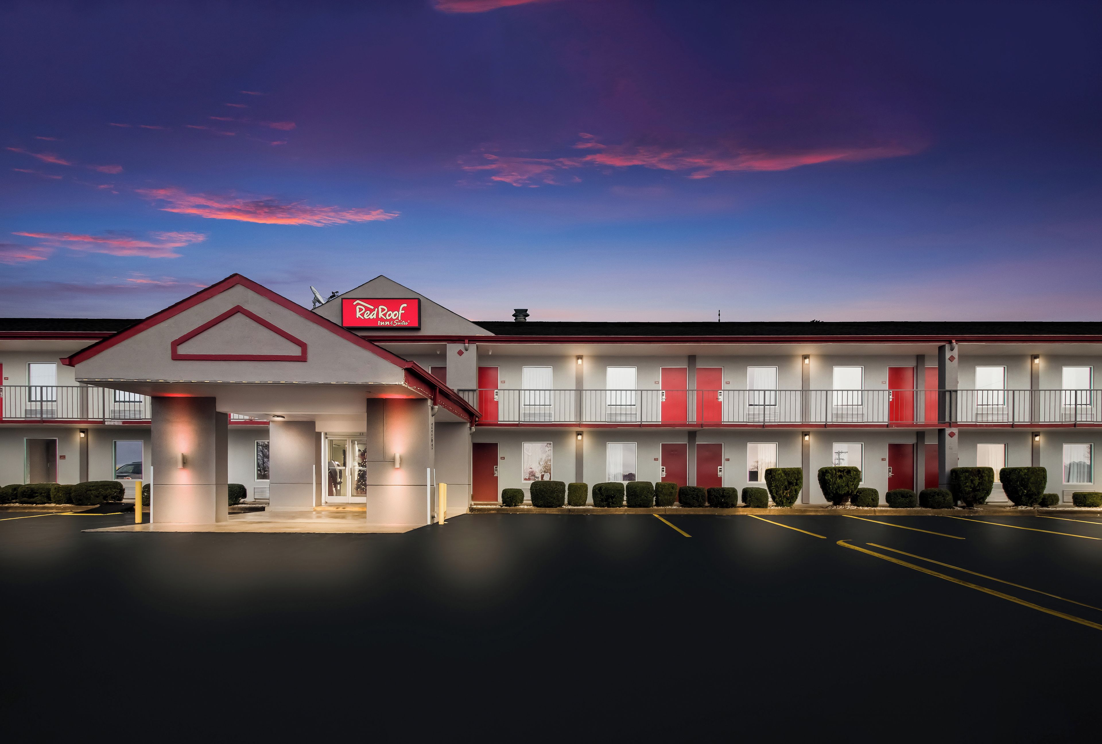 Un Red Roof Inn & Suites de dos pisos, con estacionamiento y cielo despejado.