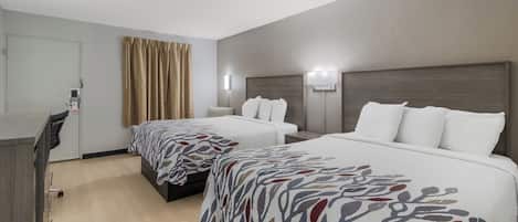A hotel room with two beds, a desk, and a chair.