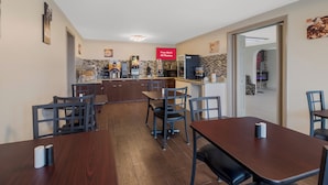 A modern cafe with wooden tables and chairs, a coffee machine, and a sign offering free Wi-Fi. - Red Roof Inn & Suites Jackson, TN (Jackson)