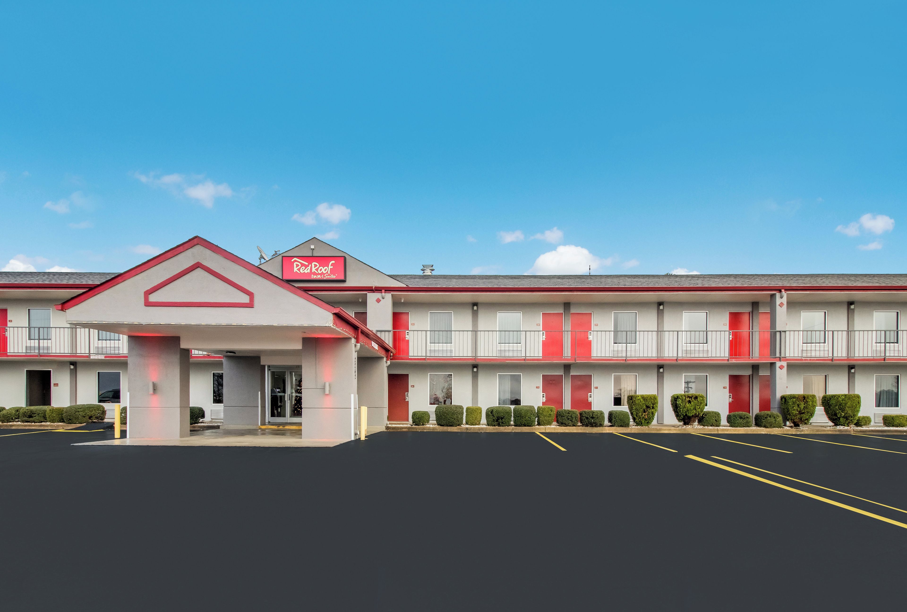 A motel with a red and white facade, multiple balconies, and a parking lot.
