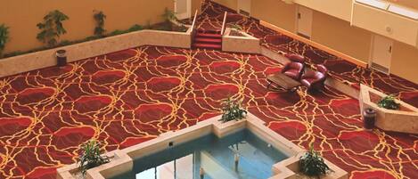 A spacious atrium with a central water feature, multiple levels with built-in seating, and a patterned carpet.