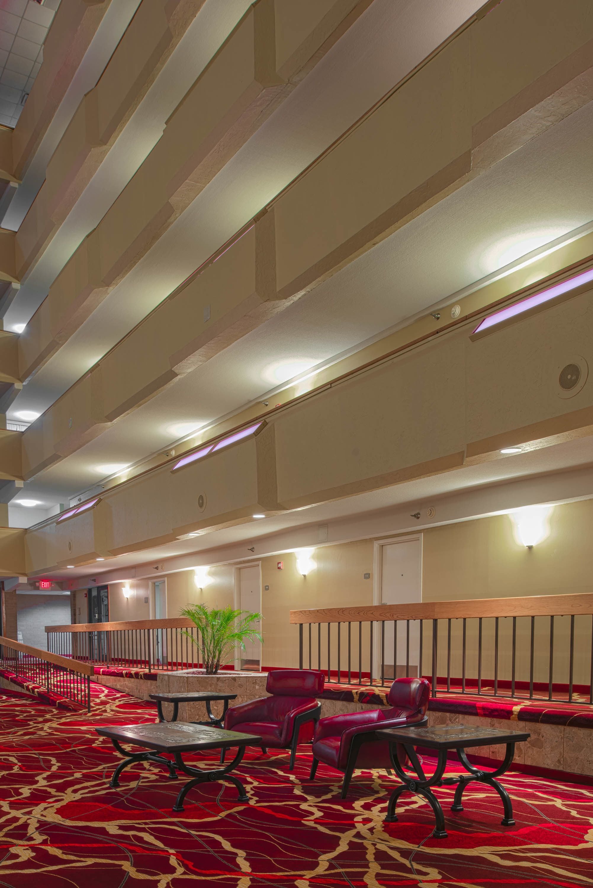 A hotel lobby with a red carpet, seating area, and a staircase.