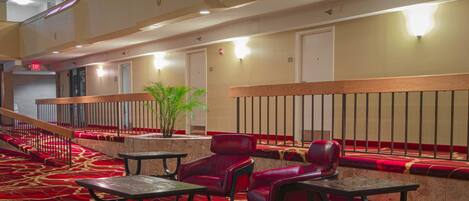 A hotel lobby with a red carpet, seating area, and a staircase.