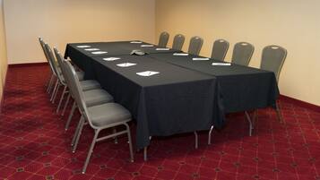 A conference room with a long table, chairs, and a carpeted floor.