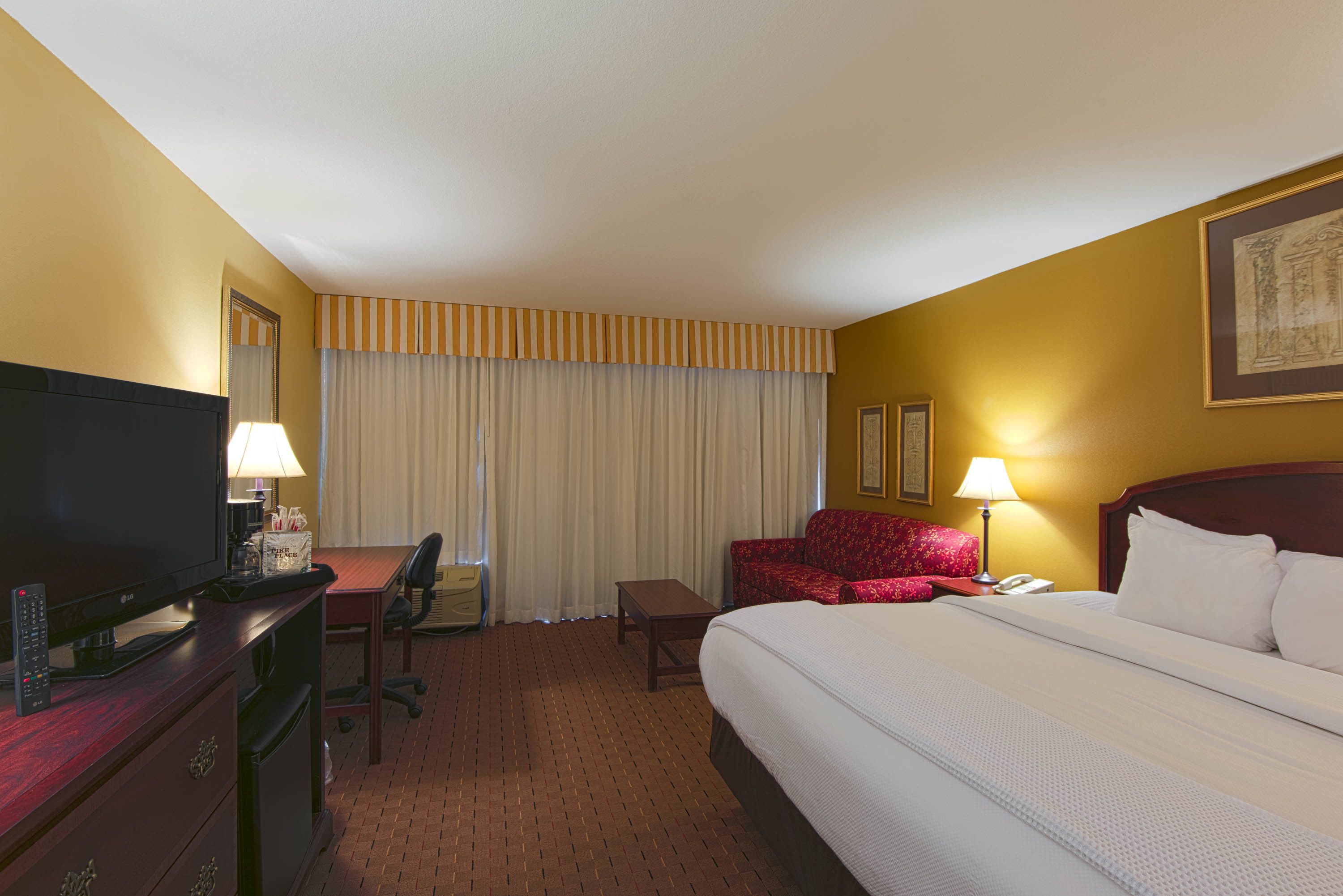A hotel room with a bed, a desk with a computer, a chair, a television, and a telephone.