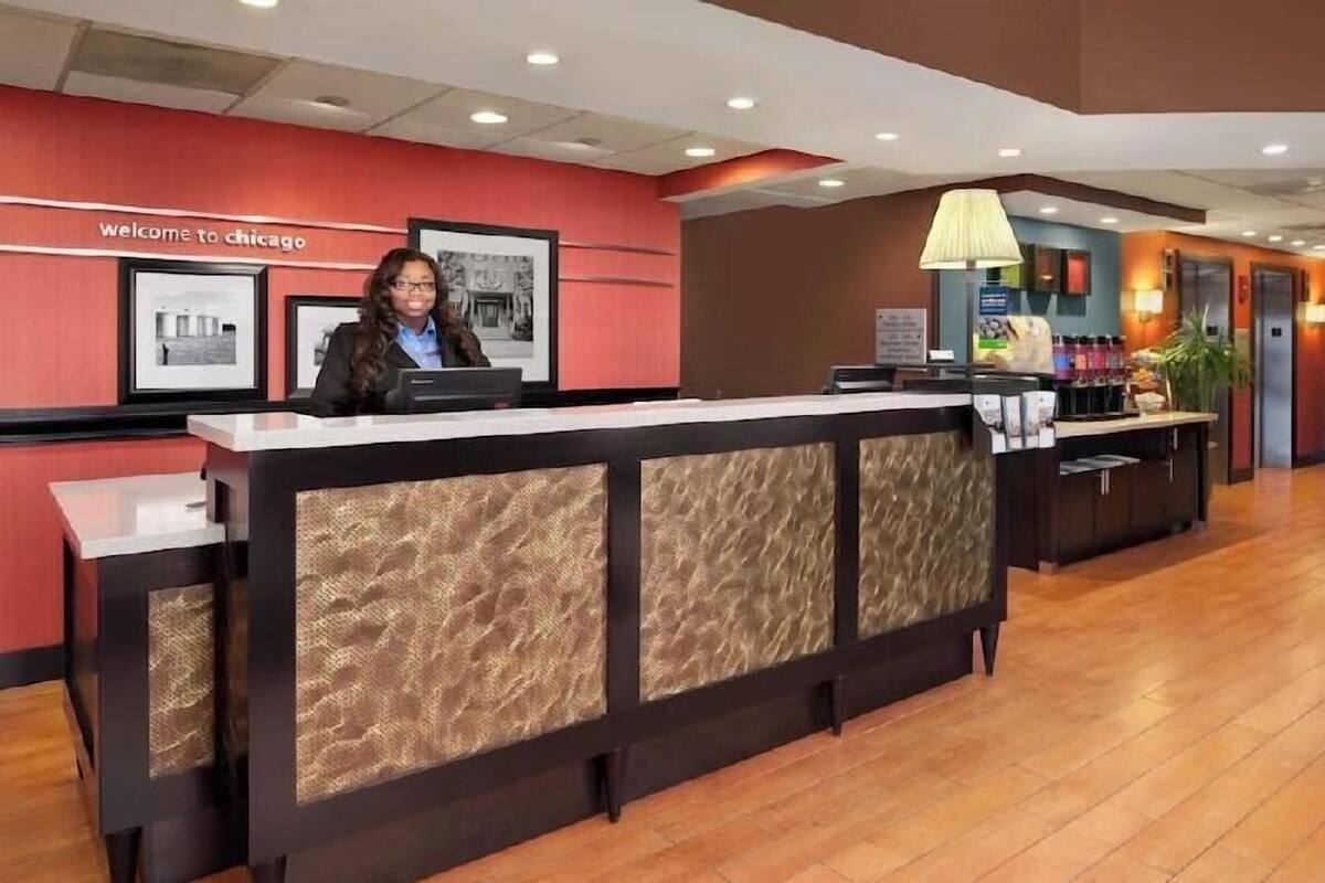 A reception desk with a 'Welcome to Chicago' sign, framed pictures on the wall, and a counter with a lamp.