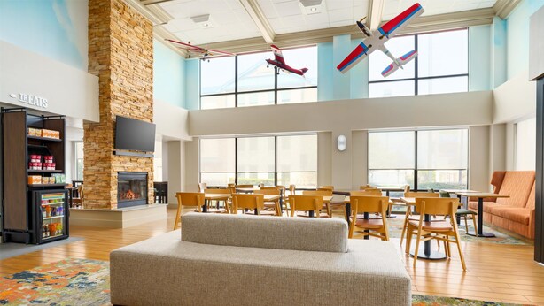 A spacious room with a fireplace, a seating area with a sofa, a dining table with chairs, and a vending machine labeled "TREATS". - Hampton Inn by Hilton Chicago-Midway Airport (Chicago)