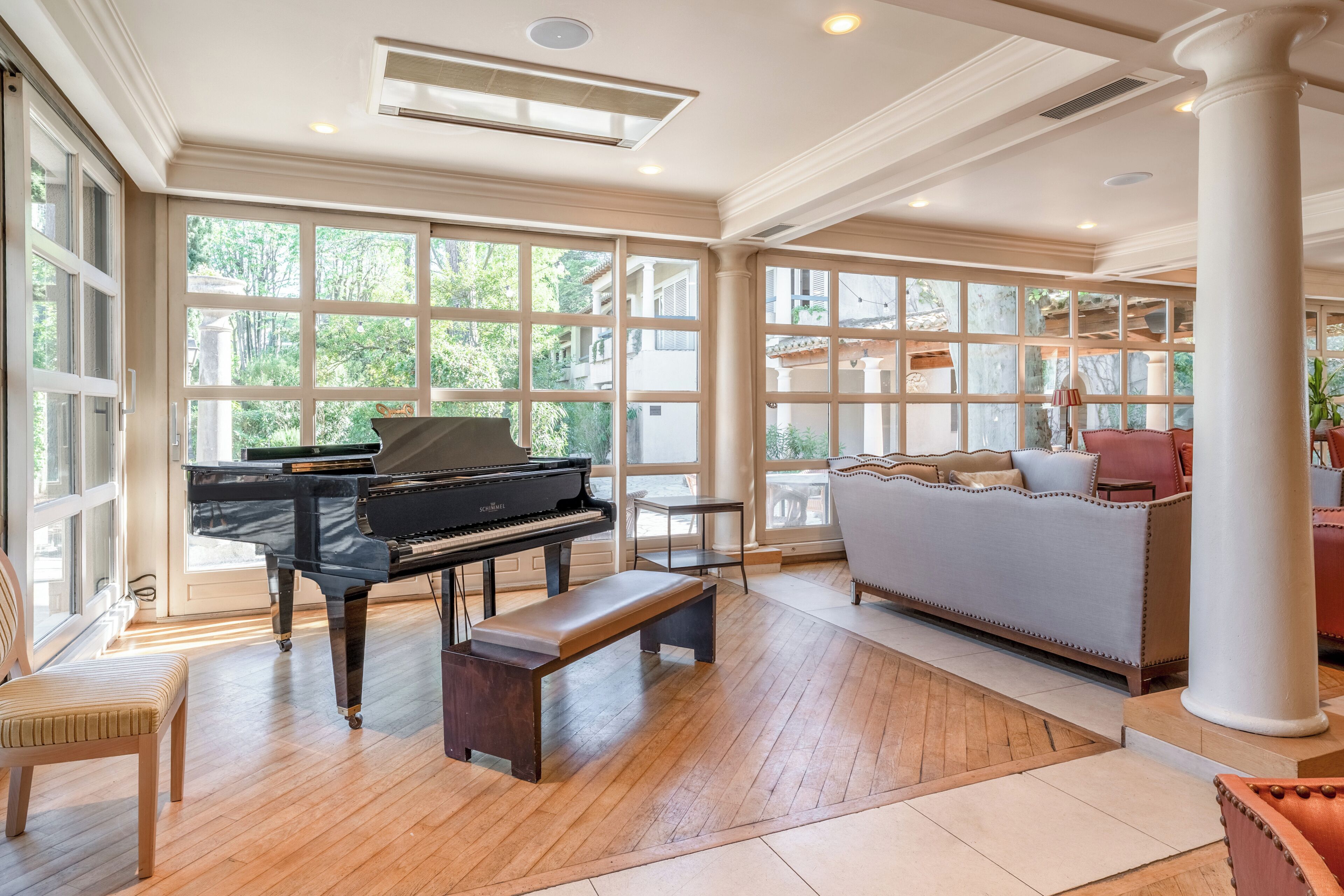 Amplia habitación con un piano de cola, un banco y un sofá.