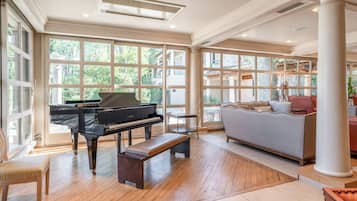 Amplia habitación con un piano de cola, un banco y un sofá.