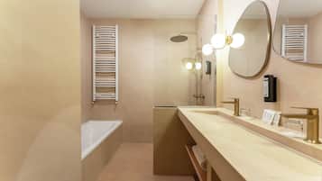 Ein modernes Badezimmer mit einer Badewanne, einer Dusche, einem Waschtisch mit Spiegel und einem Handtuchhalter.
