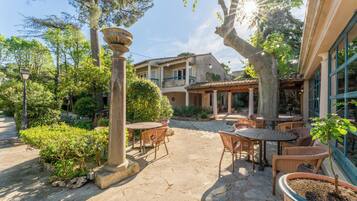 An outdoor patio area with stone flooring, wicker furniture, and a pergola structure.