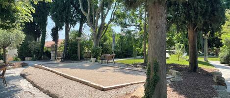 Un patio con zona pavimentada, mobiliario y árboles.