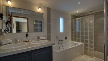 A modern bathroom with two sinks, a large bathtub, and a glass shower enclosure.