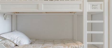 A bunk bed with a lower bunk and a top bunk, both with white bedding and a striped pillow.