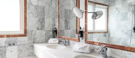 A bathroom with marble walls, two sinks, and a large mirror with a wooden frame.