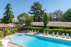 Una piscina al aire libre, sombrillas, sillones reclinables de piscina