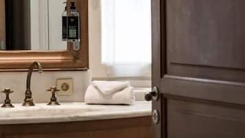 Un baño con tocador de madera, un espejo, grifo y ventana con vistas.