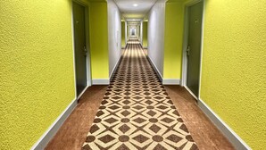 A hallway with yellow walls and a patterned carpet. - Super 8 by Wyndham Harrison OH (Harrison)
