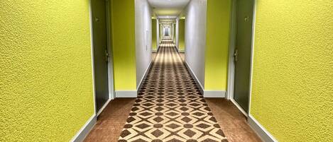 Un pasillo con paredes amarillas y una alfombra estampada.