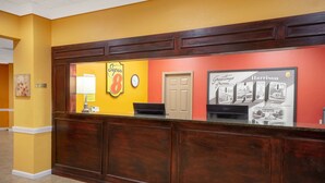 A reception desk with a clock, a sign reading "Super 8", and a framed welcome sign for Harrison. - Super 8 by Wyndham Harrison OH (Harrison)