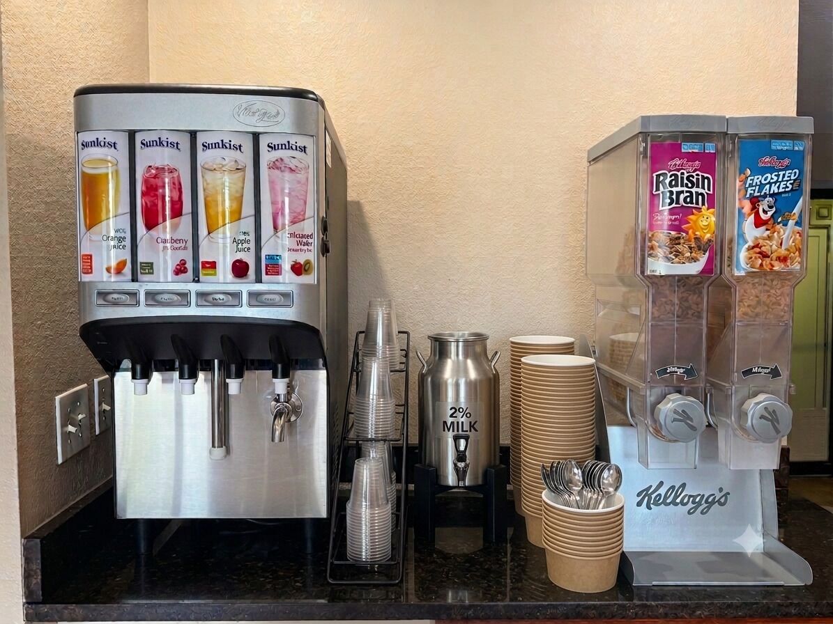 A beverage station with multiple drink dispensers, including a milk dispenser and a cereal dispenser.
