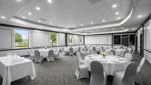 A conference room with round tables, white chairs, and a carpeted floor. - Super 8 by Wyndham Harrison OH (Harrison)