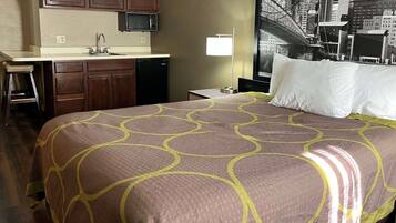 A hotel room with a bed, a desk, and a kitchenette.