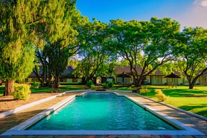 A swimming pool surrounded by trees and buildings. - Great Zimbabwe Hotel (Masvingo)