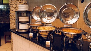 A buffet setup with multiple serving stations, each with a covered bowl and stacked plates. - Great Zimbabwe Hotel (Masvingo)