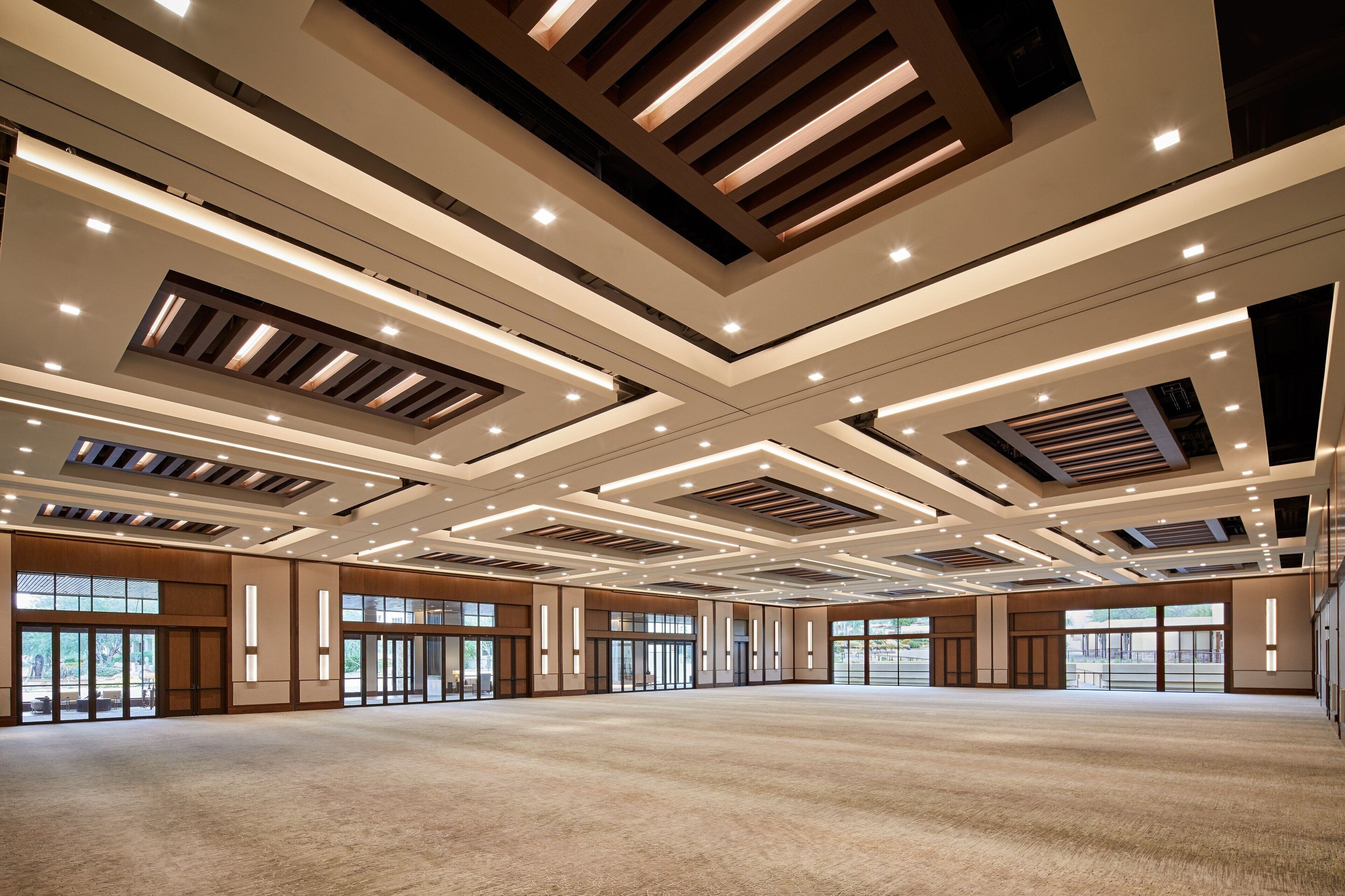 A spacious, modern hotel lobby with a high ceiling, recessed lighting, and large windows.