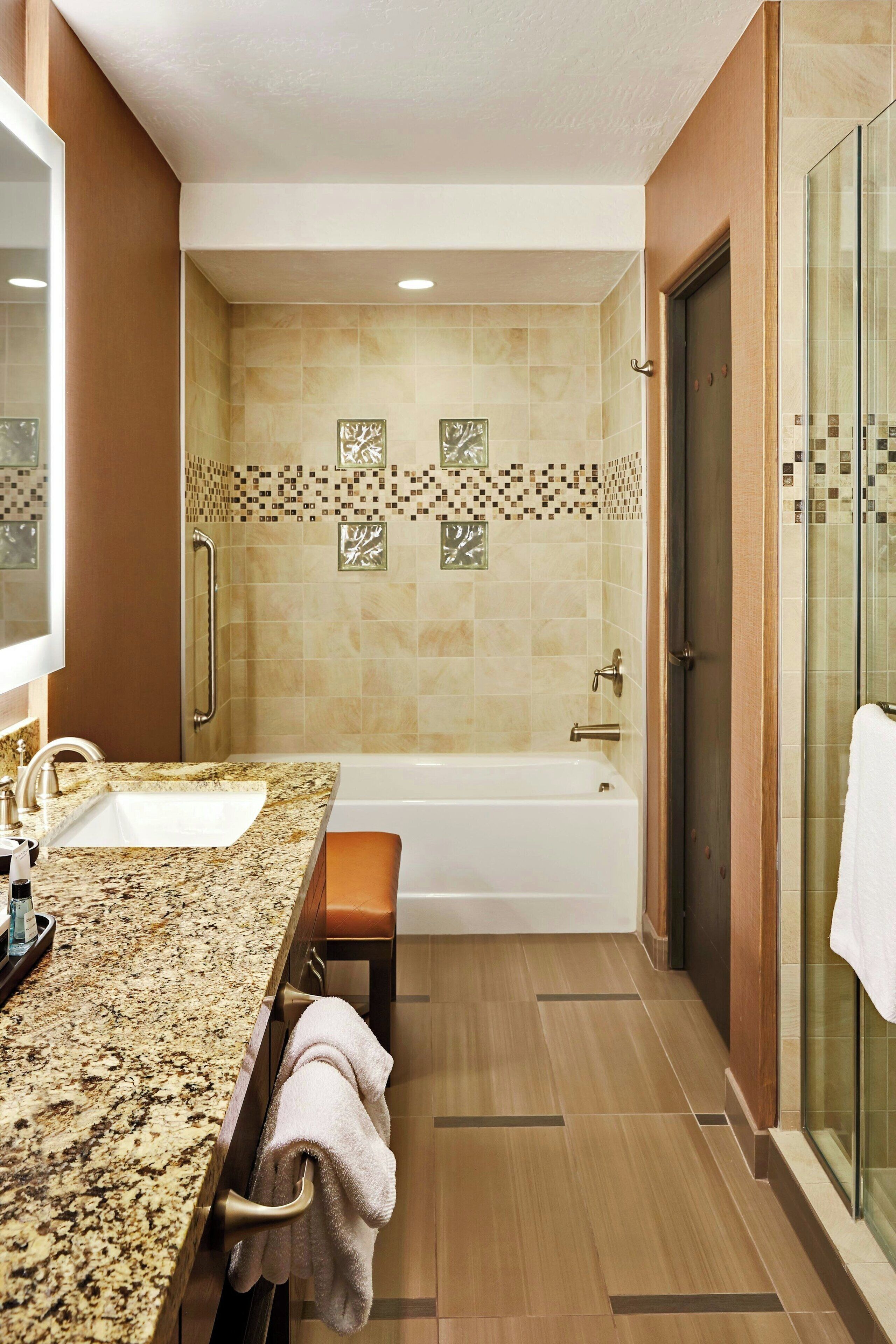 A bathroom with a sink, bathtub, and shower area.