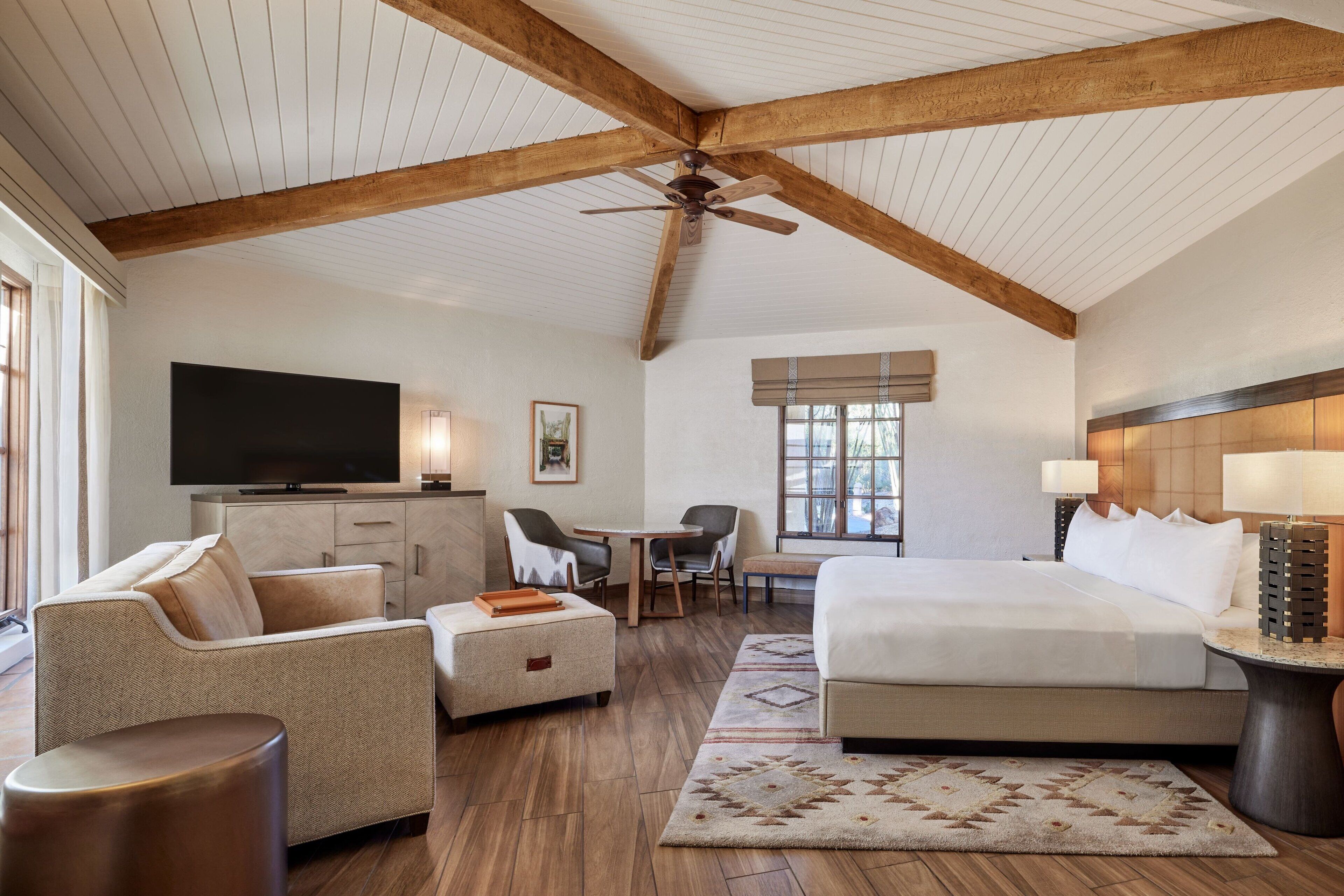 A spacious hotel room with a large bed, a desk, a sofa, and a television.