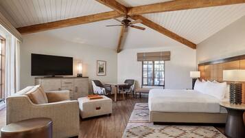 A spacious hotel room with a large bed, a desk, a sofa, and a television.