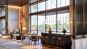 Un hall d’entrée moderne avec un plancher en bois, de grandes fenêtres et un espace salon équipé de tabourets de bar.