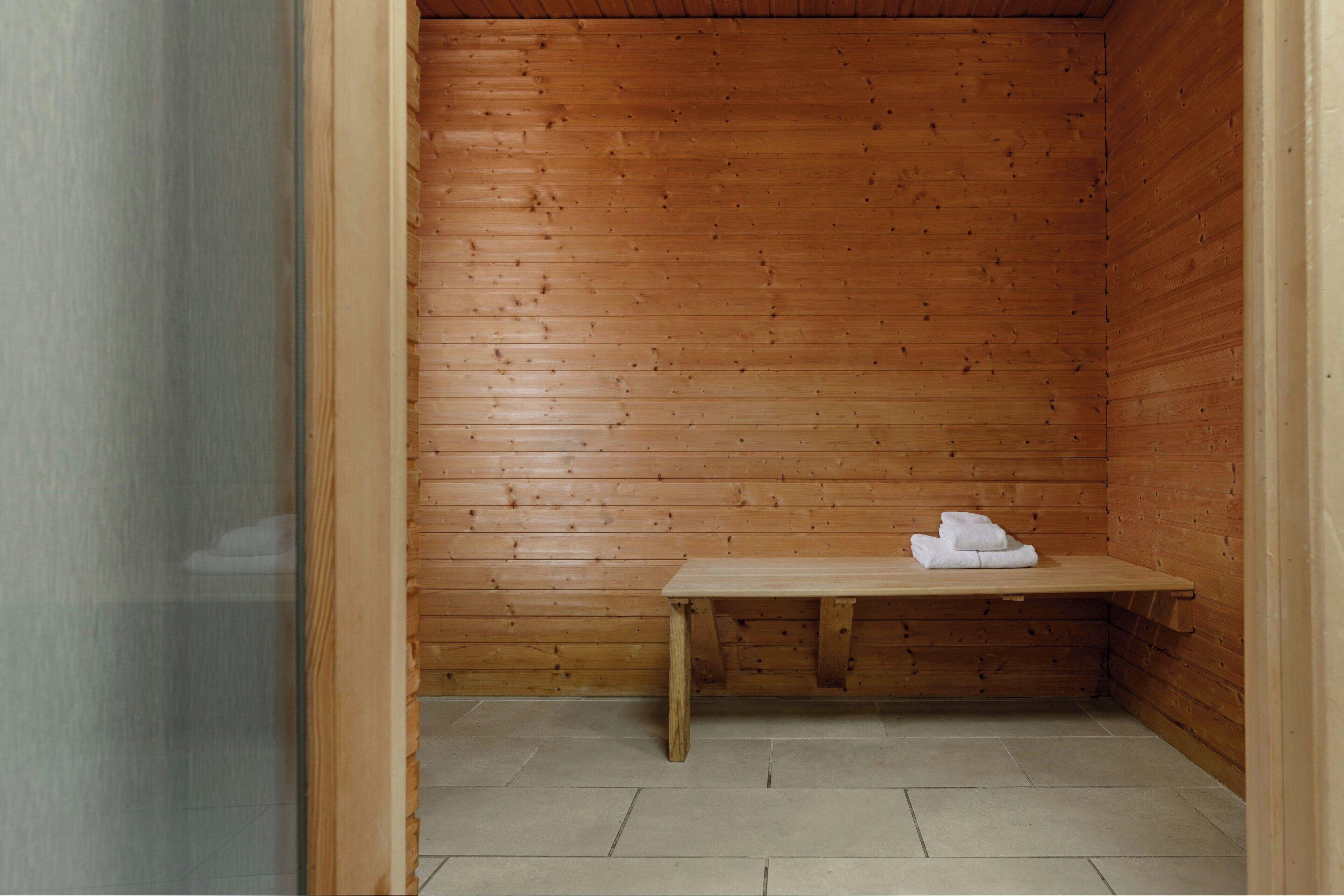 Een houten sauna met een bank en handdoeken.